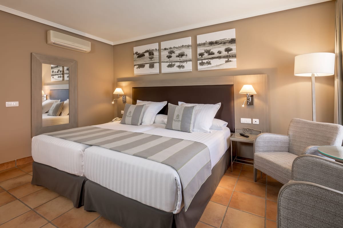 A hotel room with a large bed, two bedside tables, a chair, and a wall-mounted TV.