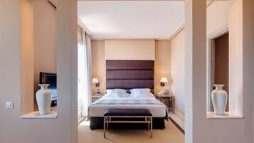 Ein Hotelzimmer mit einem großen Bett, Nachttischlampen, einem Fernseher und einer Vase auf einem Regal.