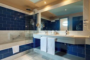Enjoy a refreshing shower in the bathroom with a large glass-enclosed shower, double sink vanity, and towel rack.