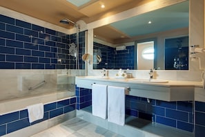 Enjoy a refreshing shower in the bathroom with a large glass-enclosed shower, double sink vanity, and towel rack.