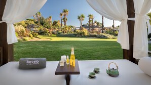 Una mesa con artículos de aseo y una toalla de Barcelona Hotels & Resorts, con vistas a un campo de golf.
