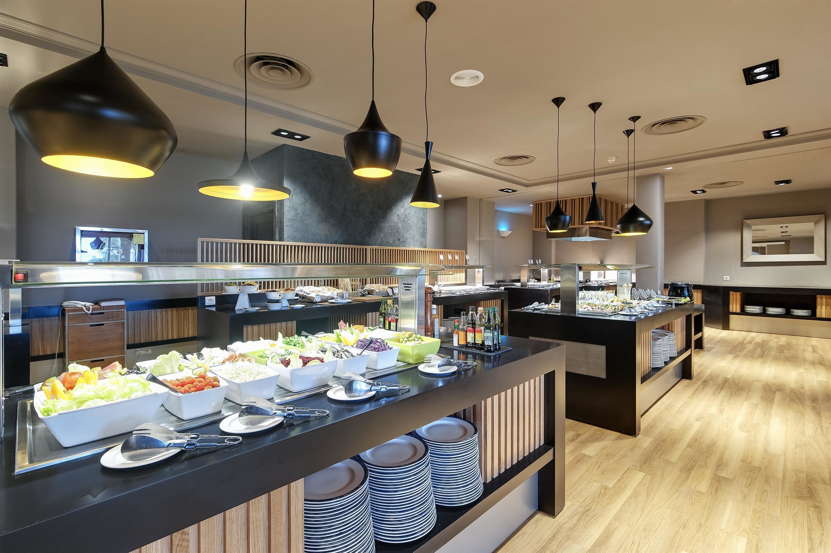 A buffet area with multiple food stations, black pendant lighting, and a modern interior design.