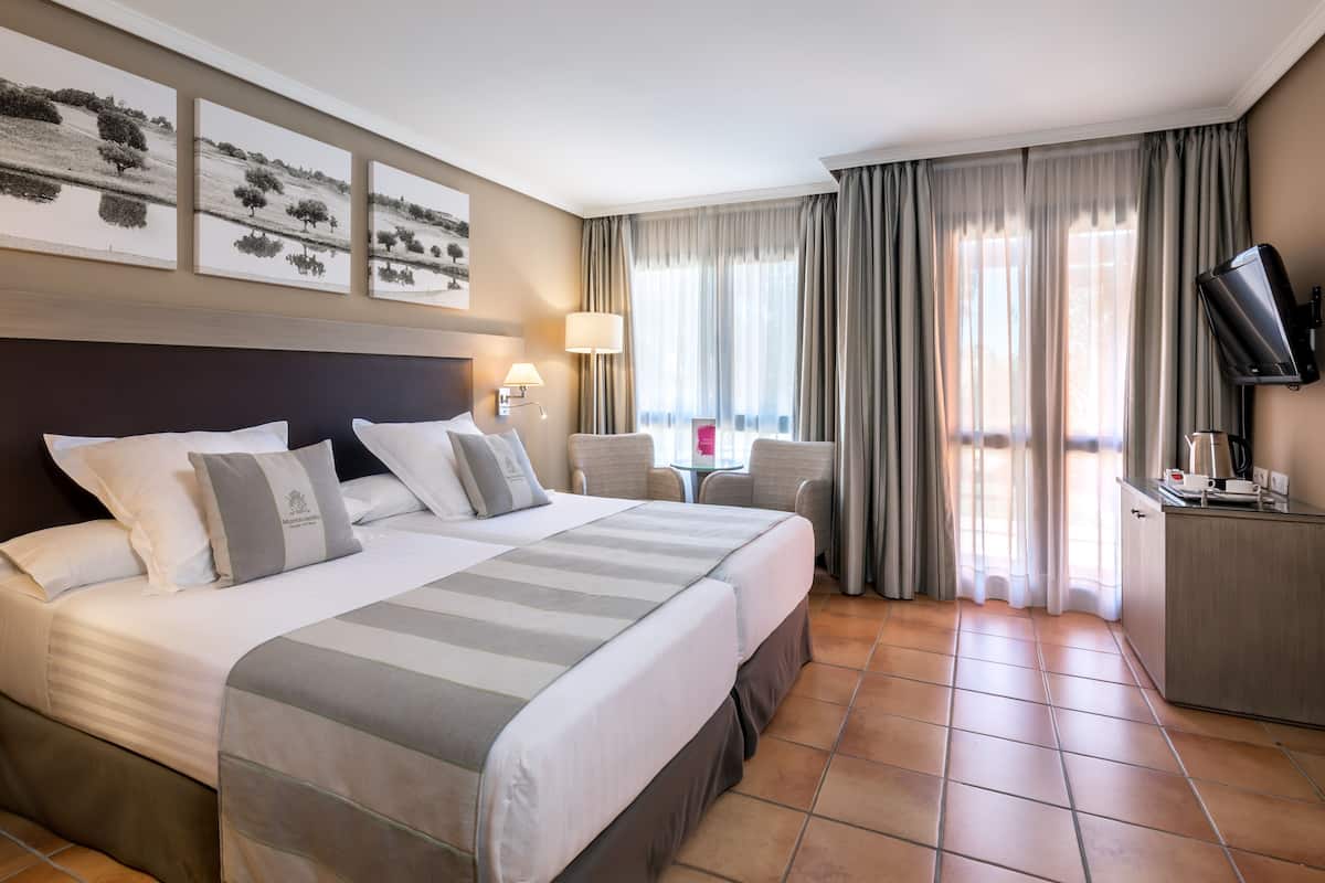 A hotel room with a large bed, two bedside tables, a TV, and a desk with a coffee maker.