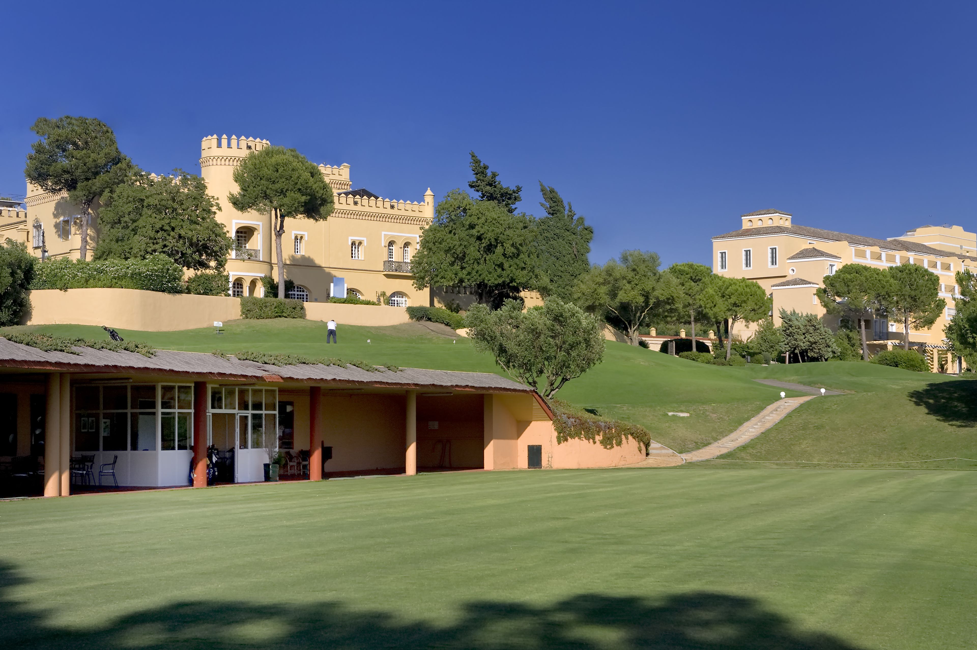 A golf course with a clubhouse and a castle-like building in the background.