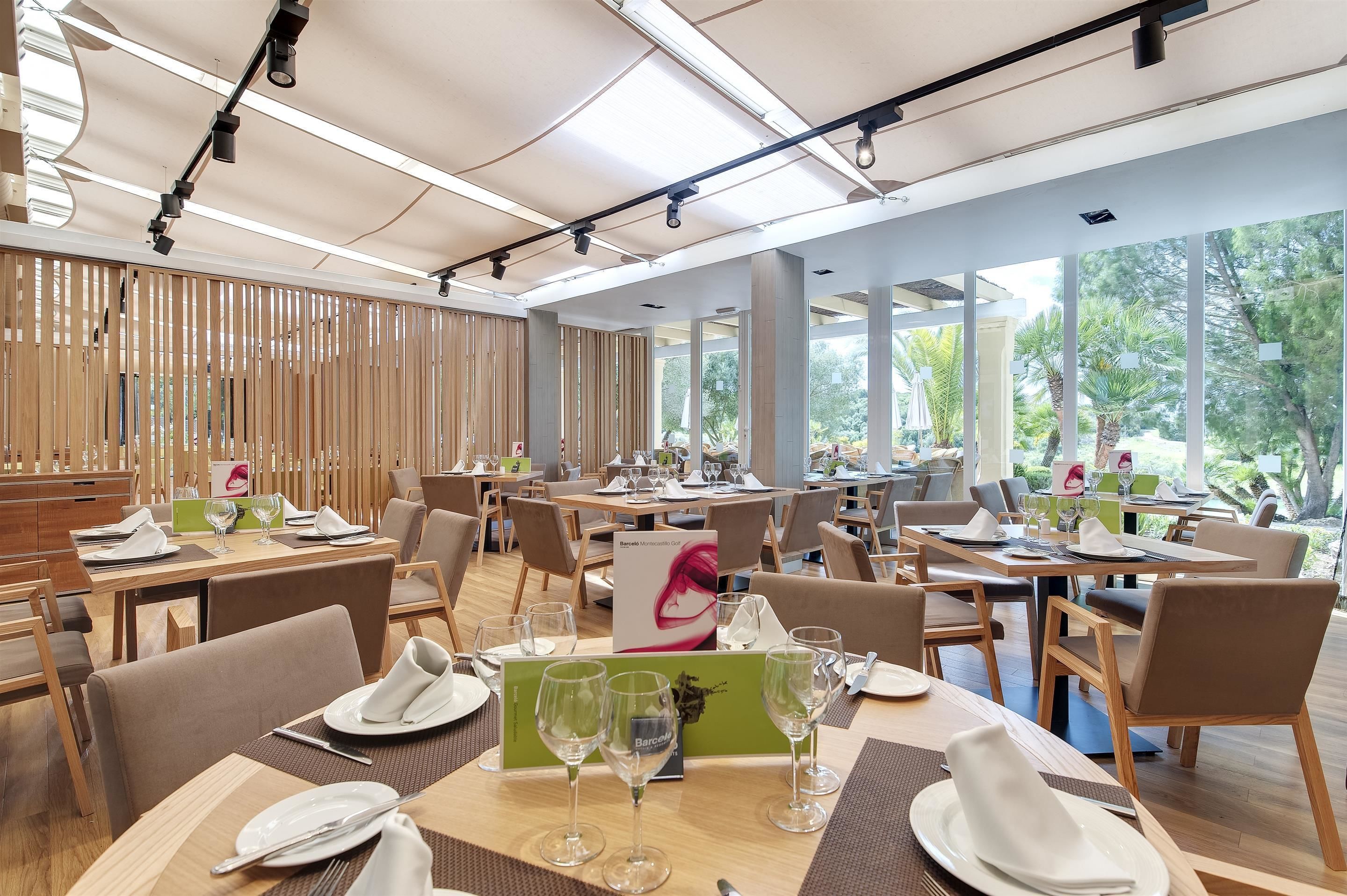 A restaurant with multiple tables set for dining, featuring a modern interior and large windows offering a view of the outdoors.