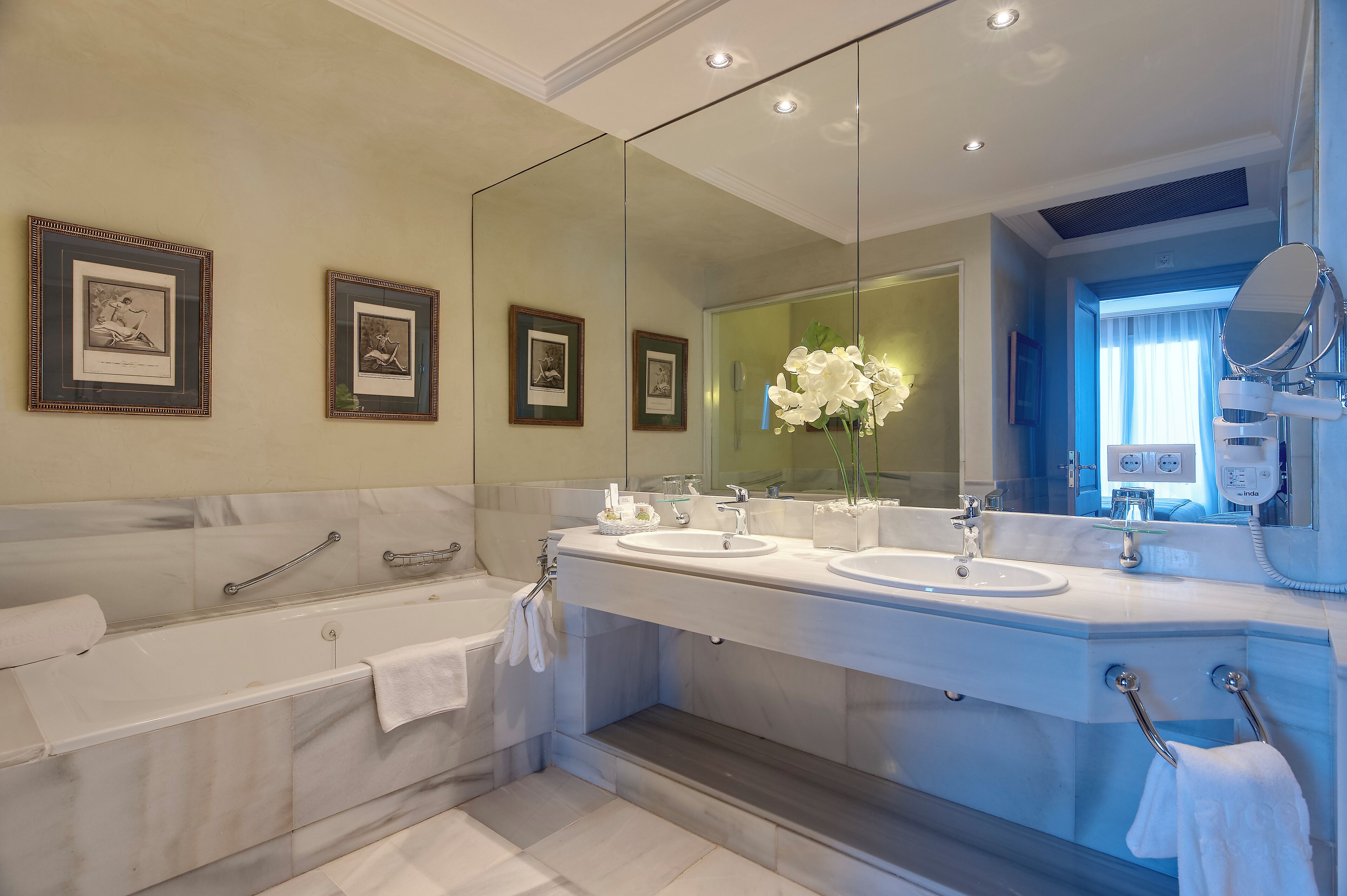A modern bathroom with a double sink vanity, a large mirror, and a bathtub.