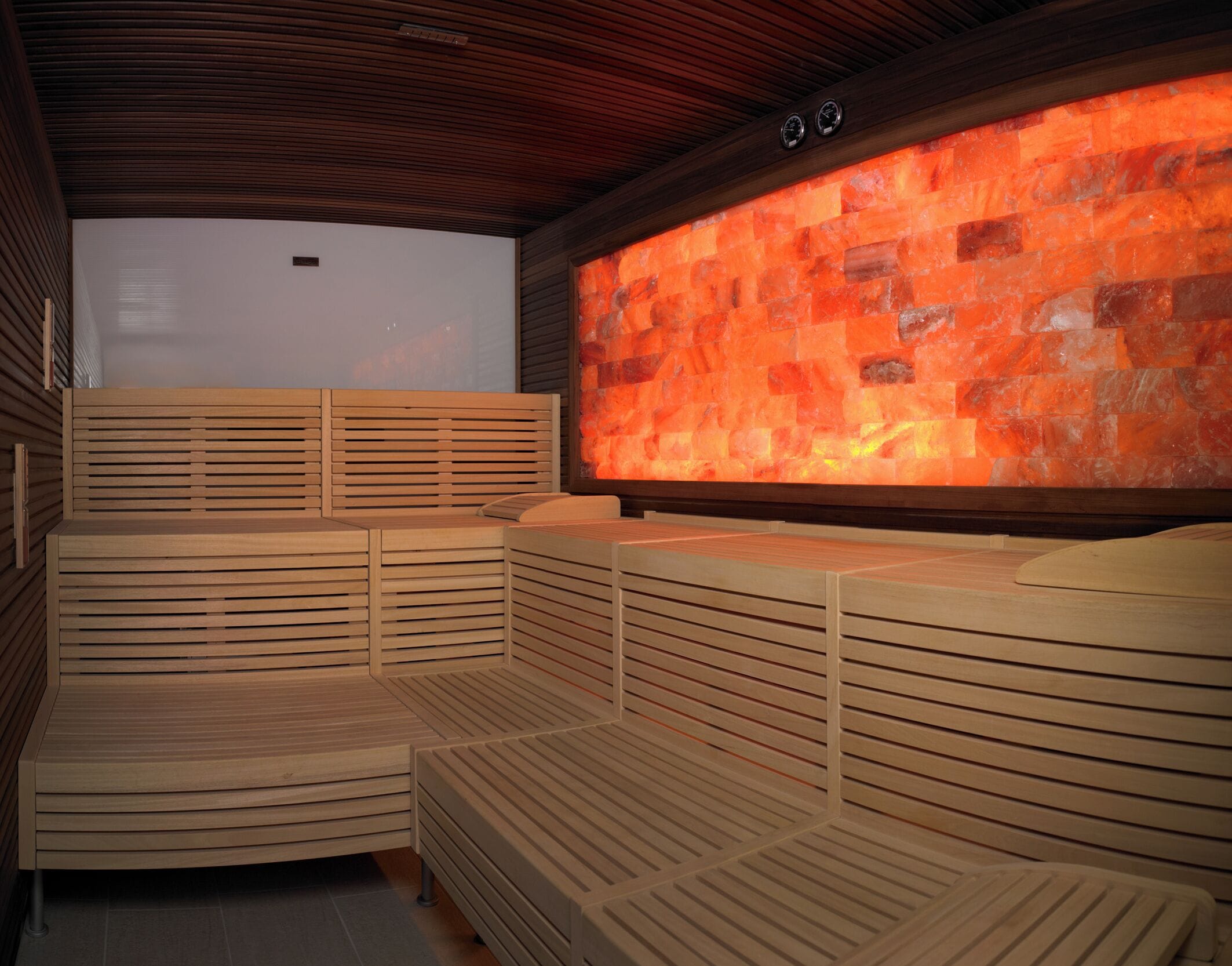 Een sauna met houten banken en een muur van hete stenen.