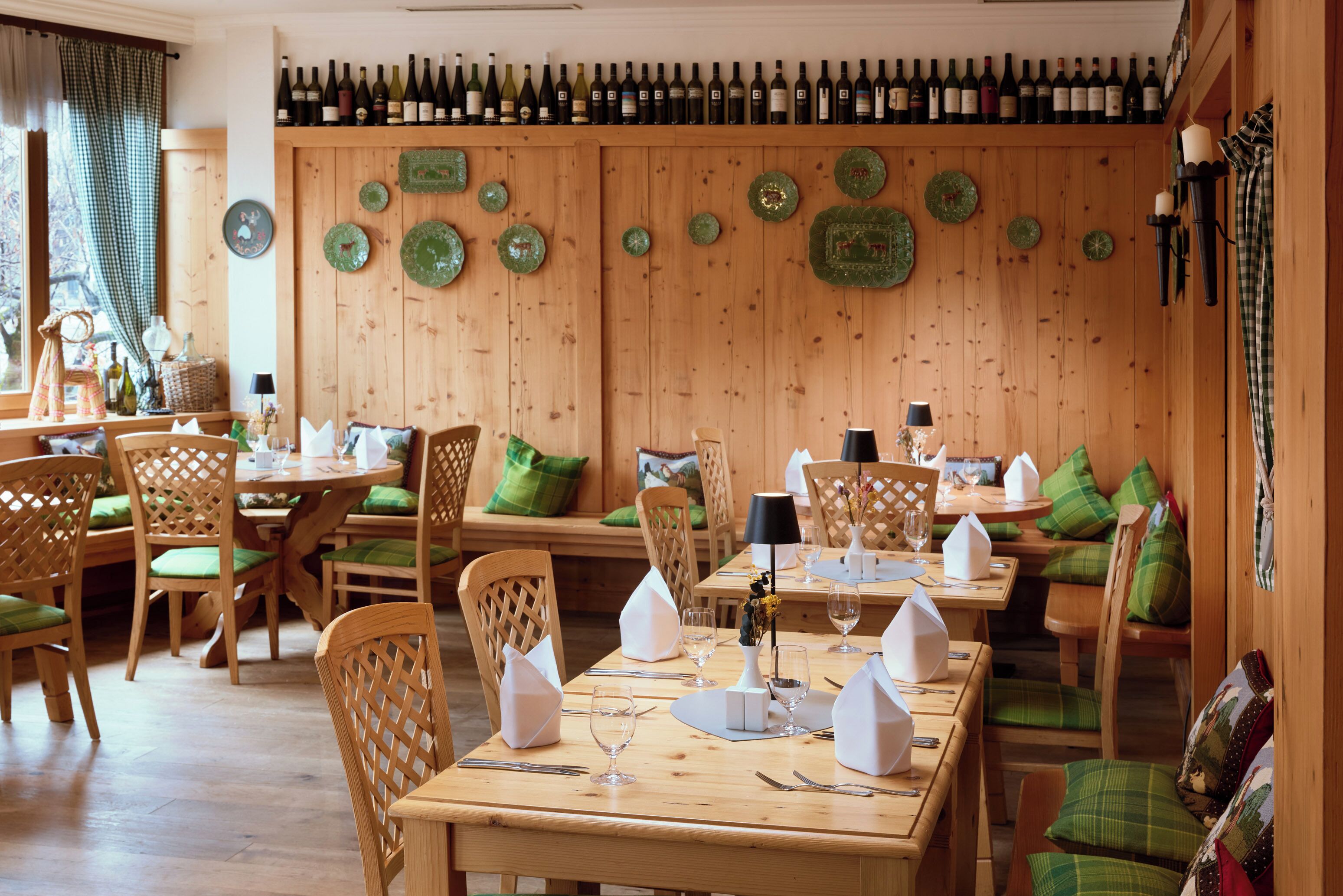 Ein Restaurant mit Holzwänden, grünen Tellern und einem Weinkühler.