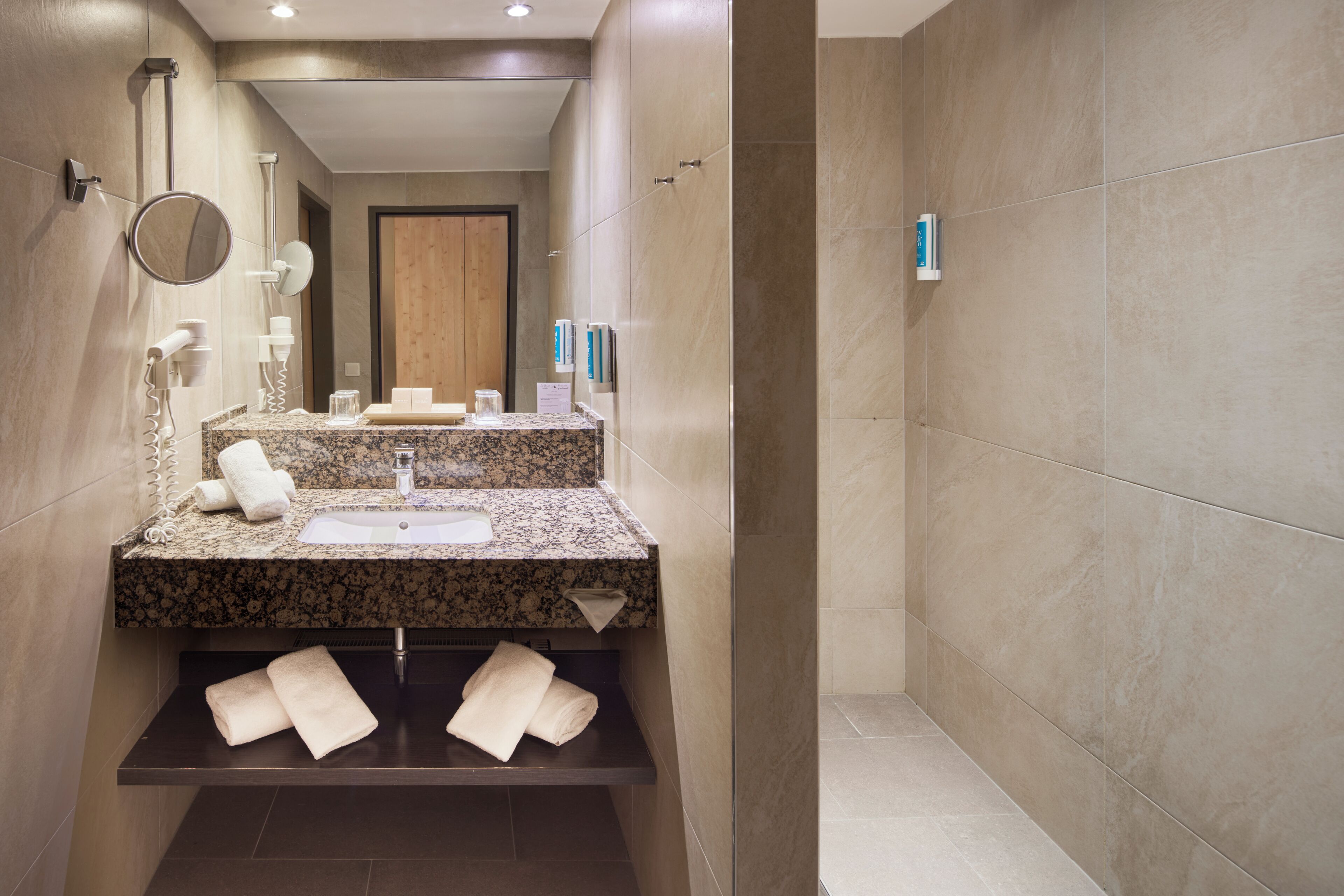 A modern bathroom with a granite countertop, a sink, a mirror, and a towel rack.