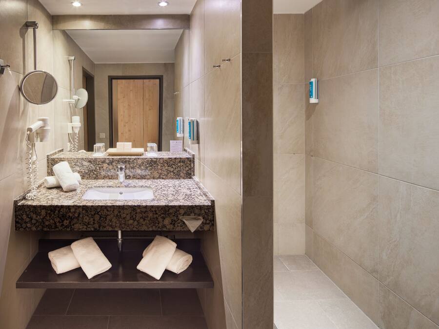 A modern bathroom with a granite countertop, a sink, a mirror, and a towel rack.