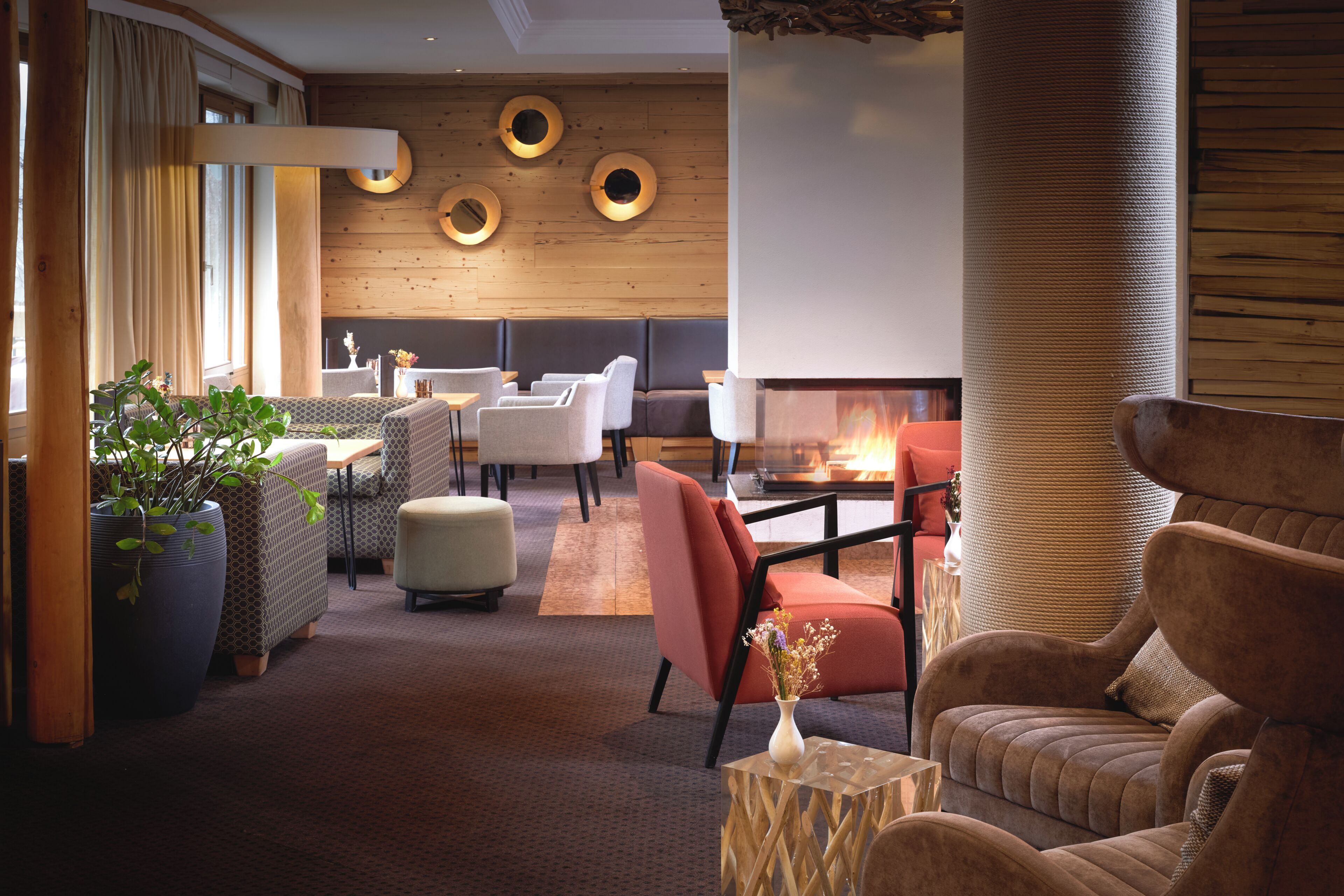 Un espacio lounge moderno con asientos, chimenea y elementos decorativos en la pared.