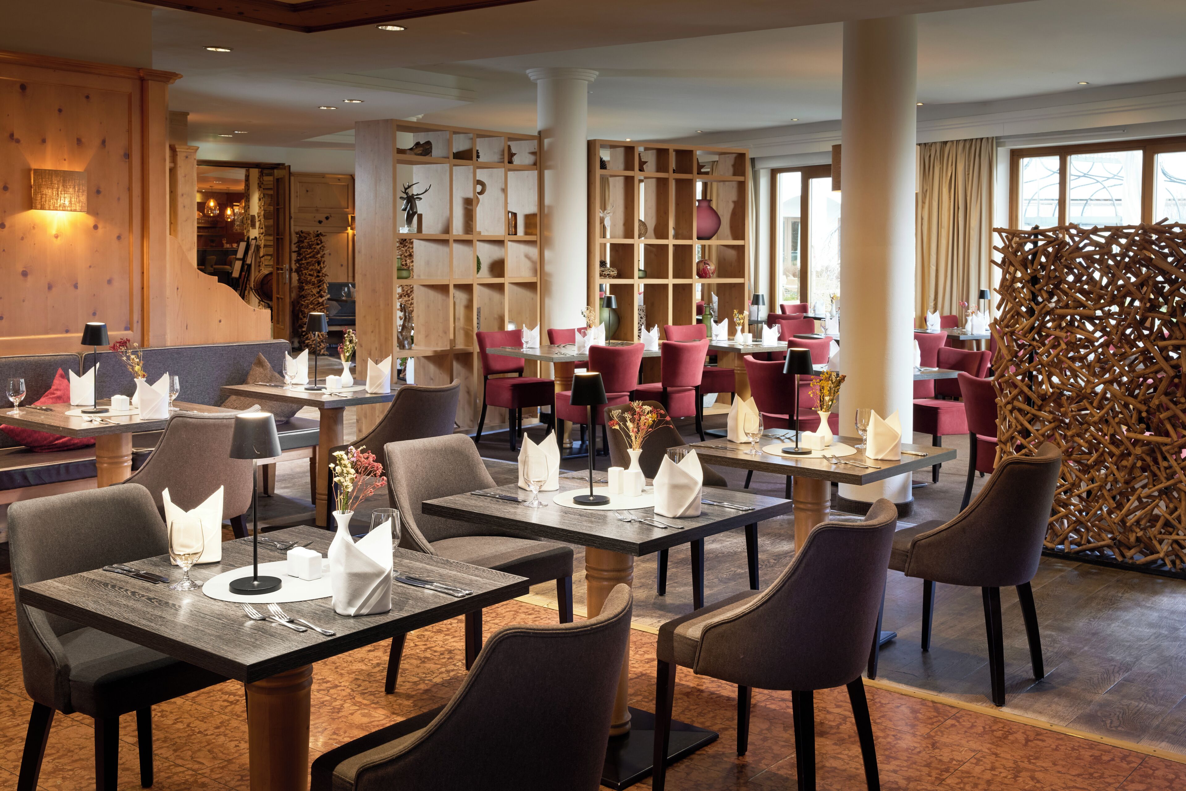 A restaurant with multiple tables, chairs, and a decorative wall with shelves.