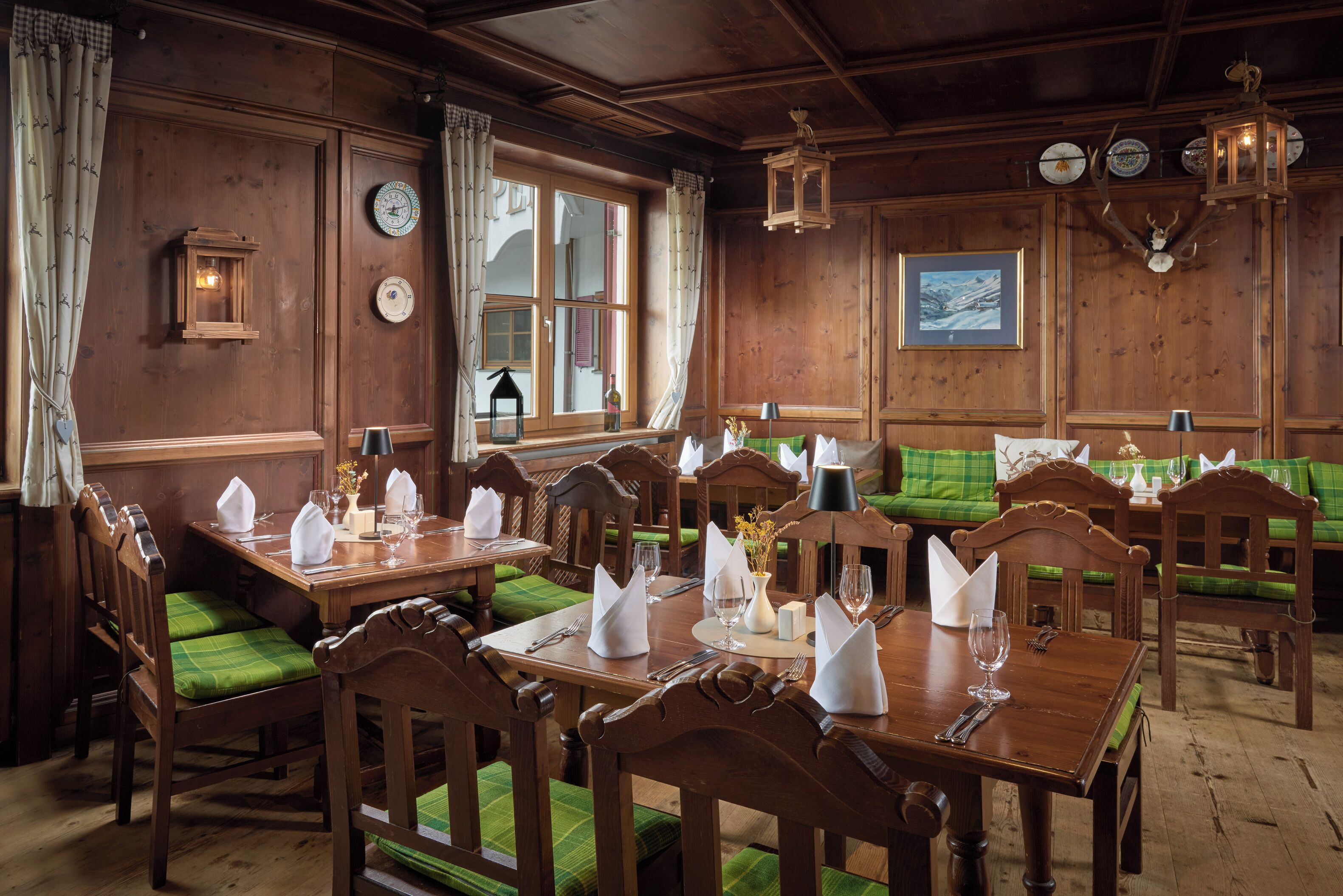 A dining area with wooden furniture, green upholstered benches, and a wooden ceiling.
