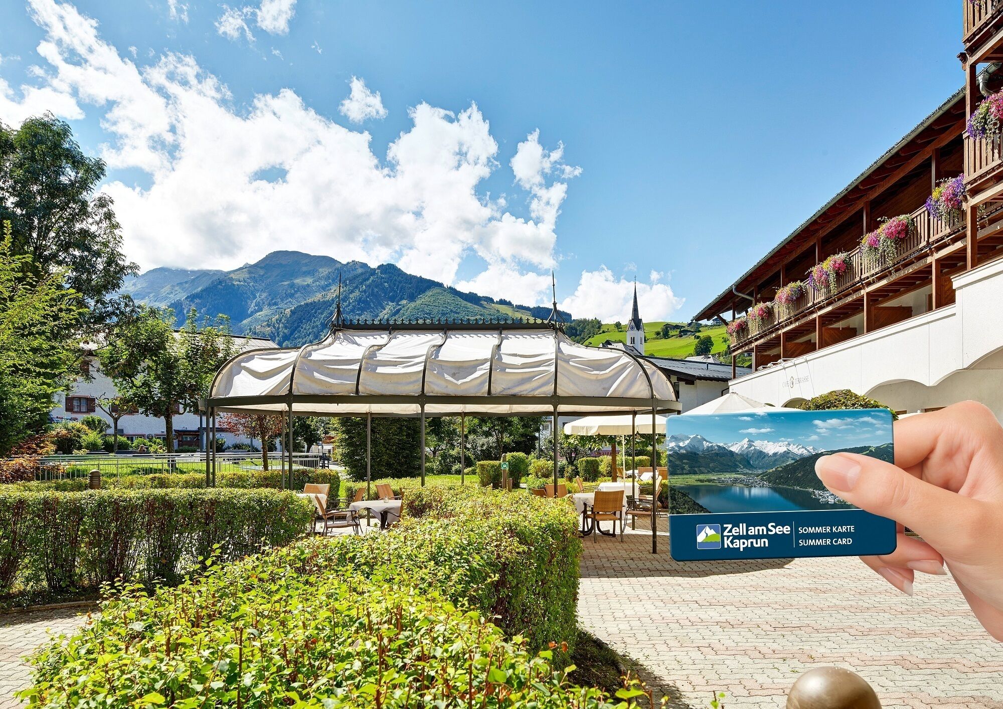 A covered outdoor seating area with a view of mountains and a church in the background.