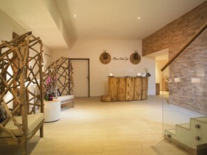 A reception area with a wooden reception desk, a bench, and a decorative wooden structure.