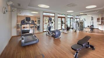 Une salle de sport équipée de tapis de course, de vélos elliptiques et d'appareils de musculation.