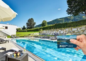Zona de piscina con sillas de descanso, una mesa con fruta y una bebida, y vistas a montañas.