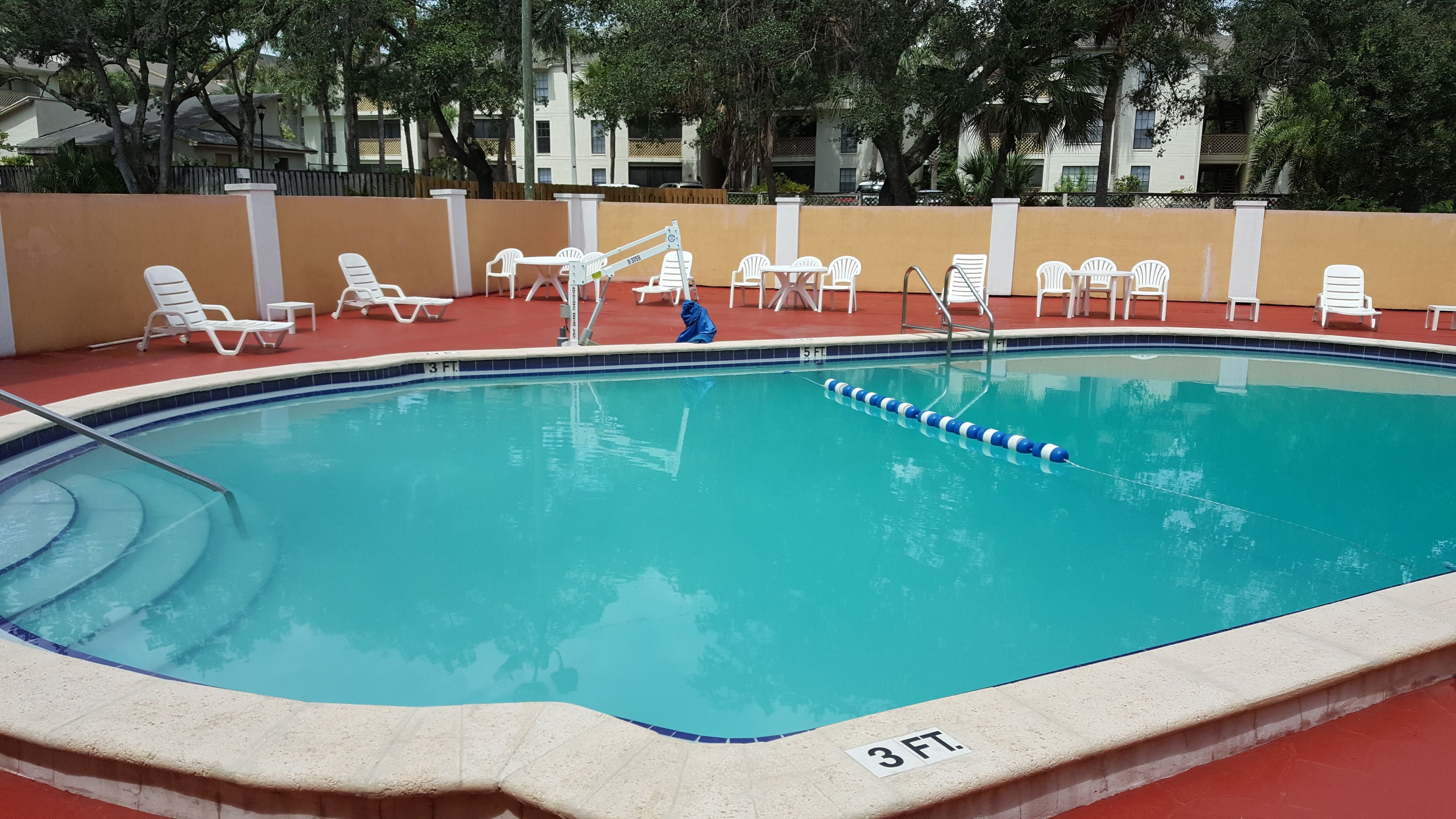 A swimming pool with lounge chairs and a diving board.