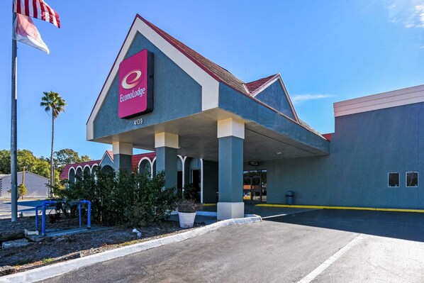 A hotel with a prominent 'EconoLodge' sign, a covered parking area, and a palm tree in the foreground. - Econo Lodge Tampa near Busch Gardens (Tampa)