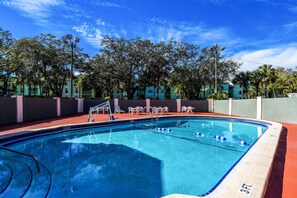 A swimming pool with a 3 FT depth marker, surrounded by a red deck and white chairs. - Econo Lodge Tampa near Busch Gardens (Tampa)