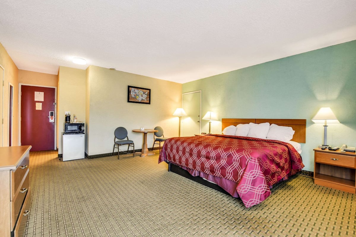 Ein Hotelzimmer mit Bett, Schreibtisch, Stuhl und einer kleinen Küche.