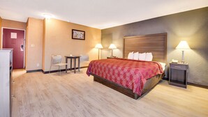 Habitación de hotel con cama, dos mesitas de noche con lámparas, un escritorio con silla y una pequeña mesa con otra silla.