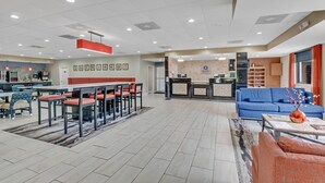 Un hall d’entrée spacieux avec un comptoir de réception, un canapé bleu et un coin repas doté d’un bar.
