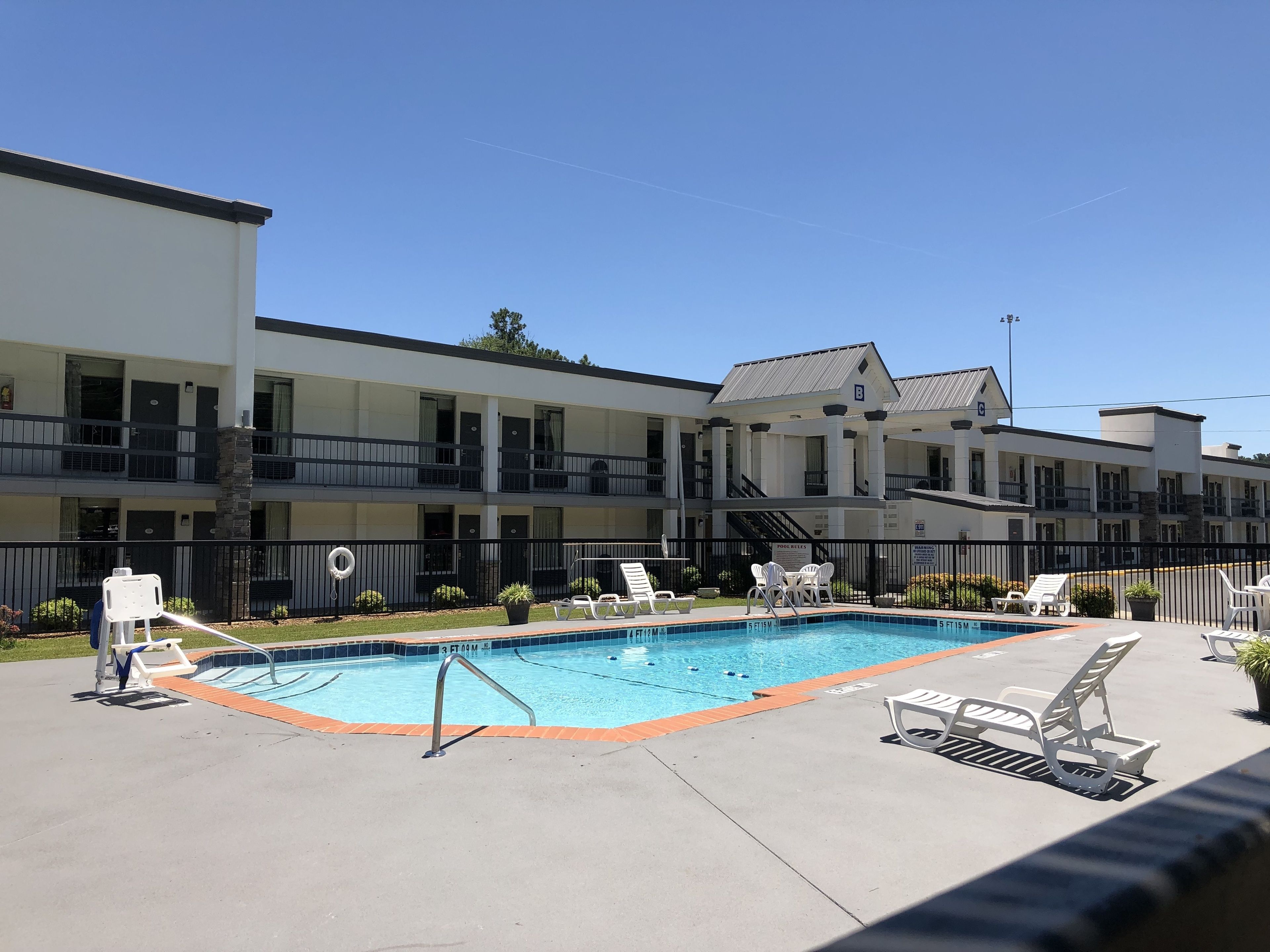 A pool area with lounge chairs and a building with multiple balconies.