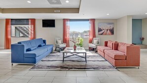 Un salon spacieux avec un canapé bleu, un canapé rouge et une table basse sur laquelle est posé un vase.
