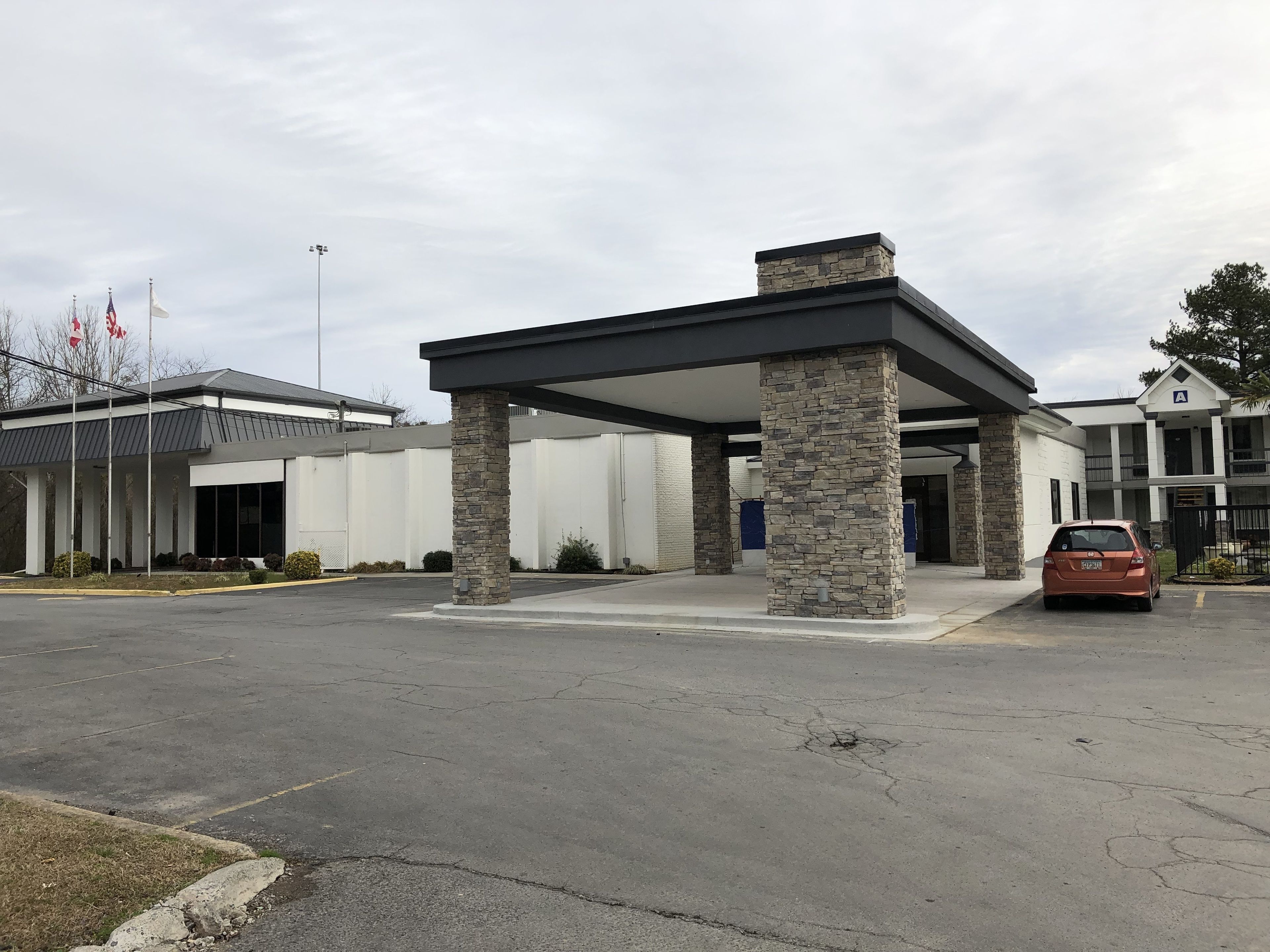 A covered parking area with stone pillars and a car parked inside.