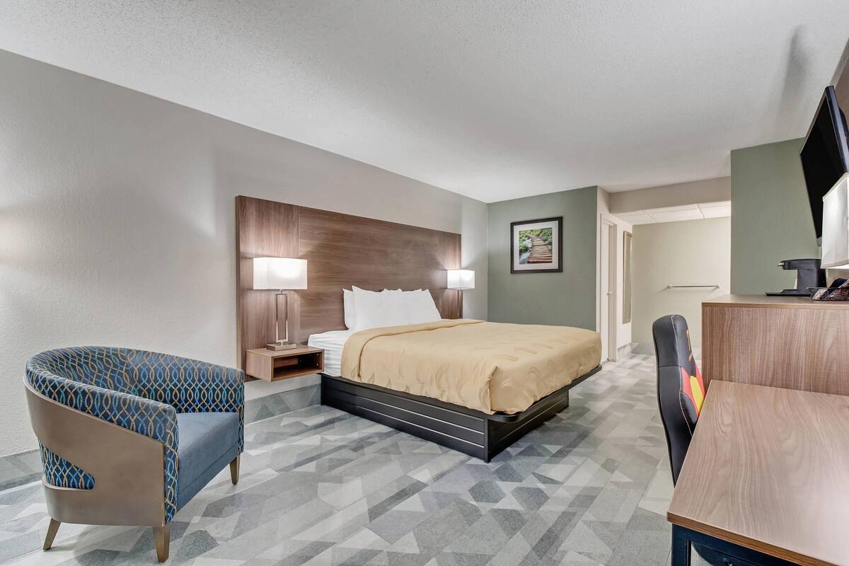 Ein Hotelzimmer mit Bett, Schreibtisch, Stuhl und Fernseher.