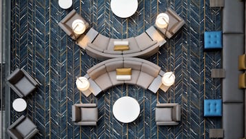 A modern lounge area with a curved sofa arrangement, multiple seating options, and a patterned floor.