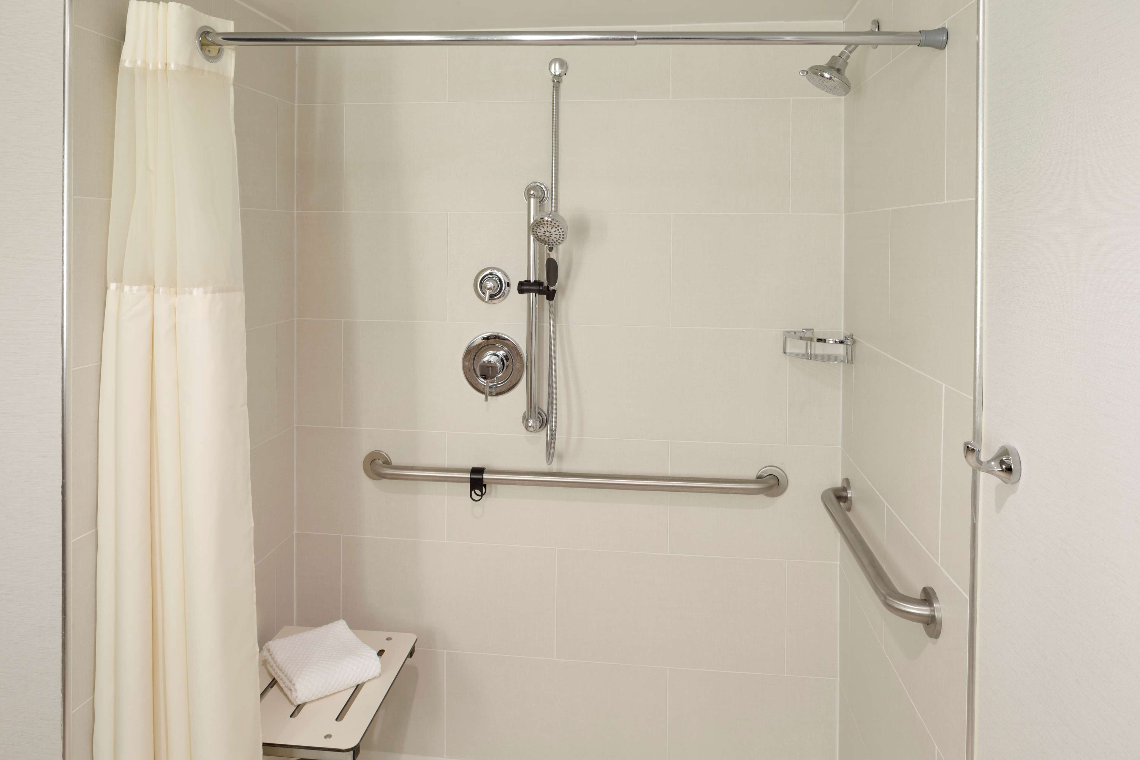 A shower with a grab bar, a towel rack, and a showerhead.