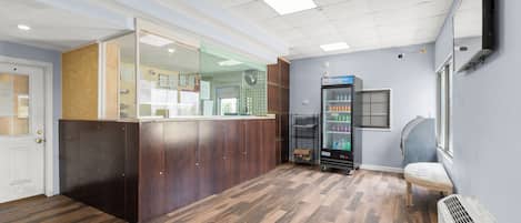 A reception area with a wooden counter, a glass partition, a vending machine, and a bench.