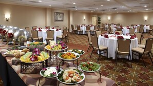 Une salle de banquet avec des tables rondes disposées pour le repas, entourées de chaises.