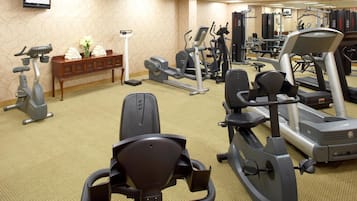 A hotel gym with various exercise equipment including treadmills, stationary bikes, and weight machines.