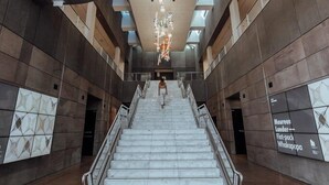 A modern interior with a curved staircase, metallic railings, and a patterned wall.
