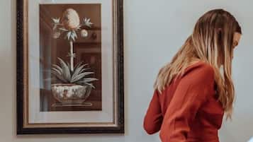 Uma pessoa sentada em uma cadeira branca em um quarto com um quadro na parede.