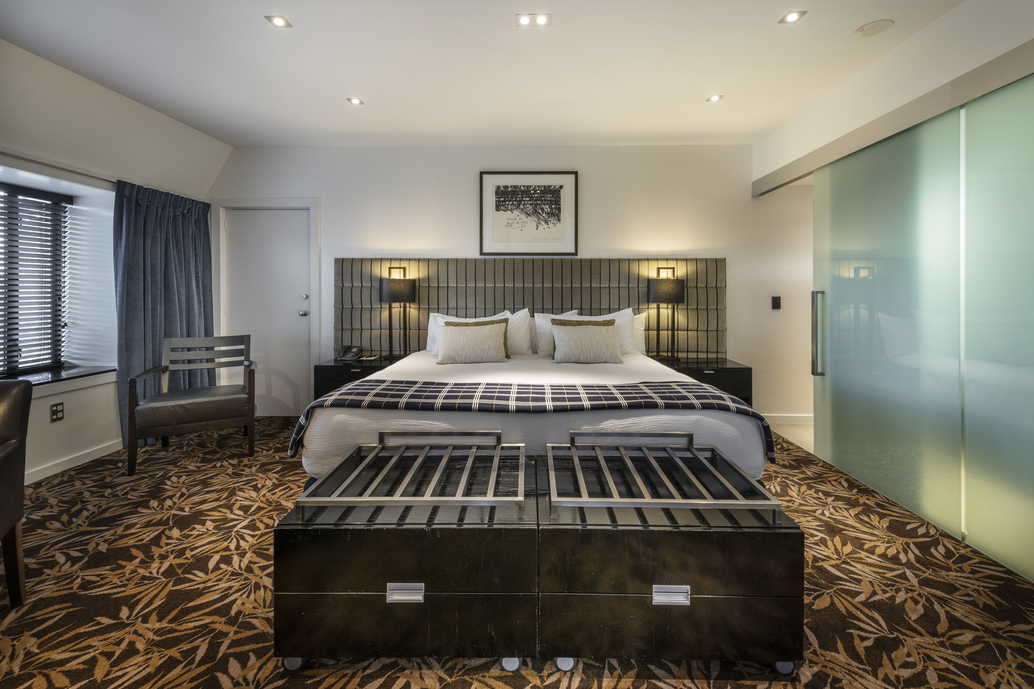 A modern hotel room with a large bed, a desk, and a chair.