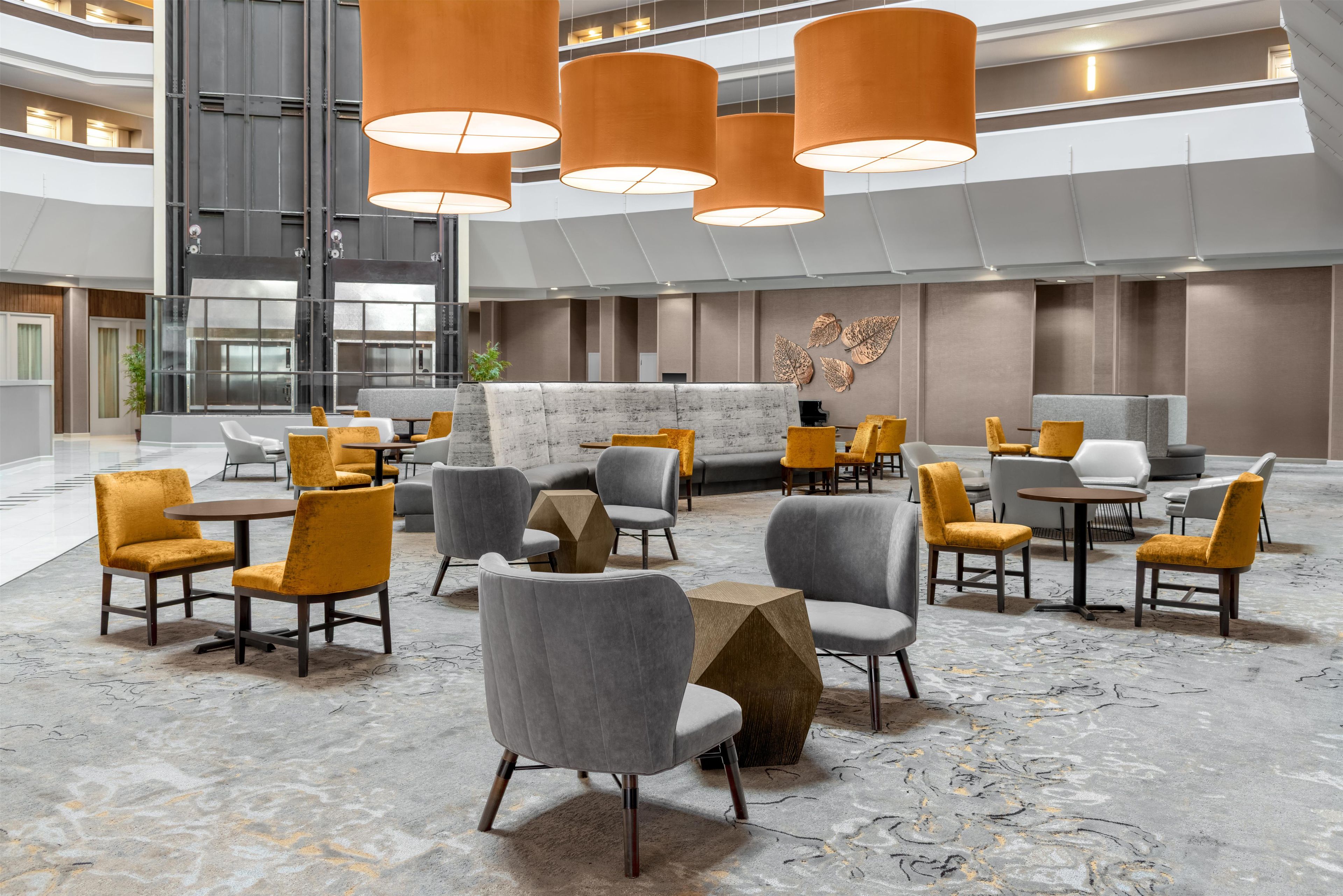 A spacious lobby with multiple seating areas, a reception desk, and a modern chandelier.