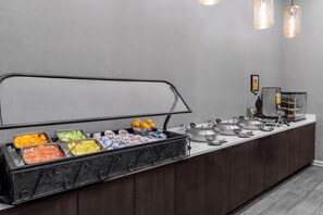 A buffet setup with various food items and condiments.