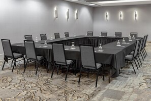 Une salle de conférence avec une longue table, des chaises et de la verrerie.