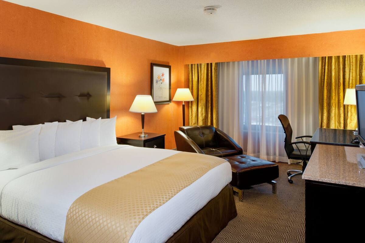 Ein Hotelzimmer mit einem großen Bett, einem Schreibtisch, einem Stuhl und einem Fernseher.