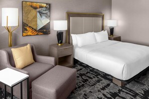 Une chambre d’hôtel avec un lit, un canapé, deux tables de chevet et une lampe.