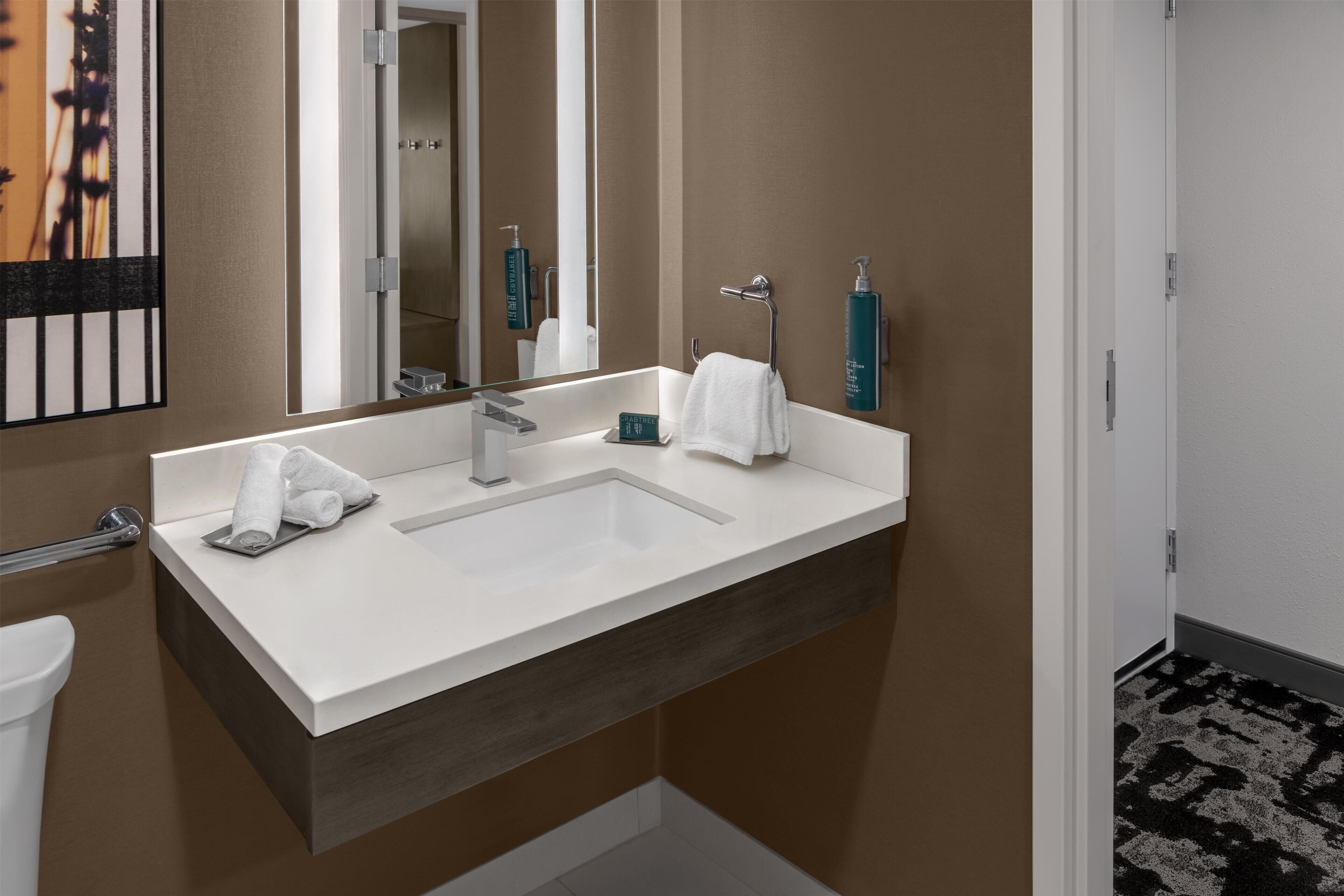 Une salle de bain moderne avec un lavabo blanc, un miroir et un porte-serviettes.