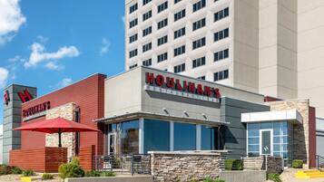 A hotel with a restaurant named 'Houlihan's' featuring a modern design with a red awning and stone facade.