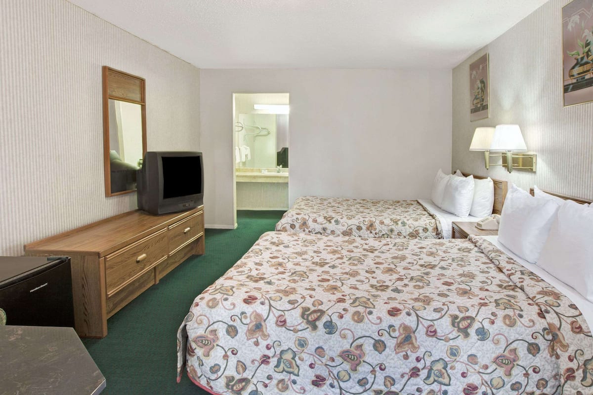 Een hotelkamer met een bed, een televisie, een dressoir en een badkamer die door een geopende deur zichtbaar is.