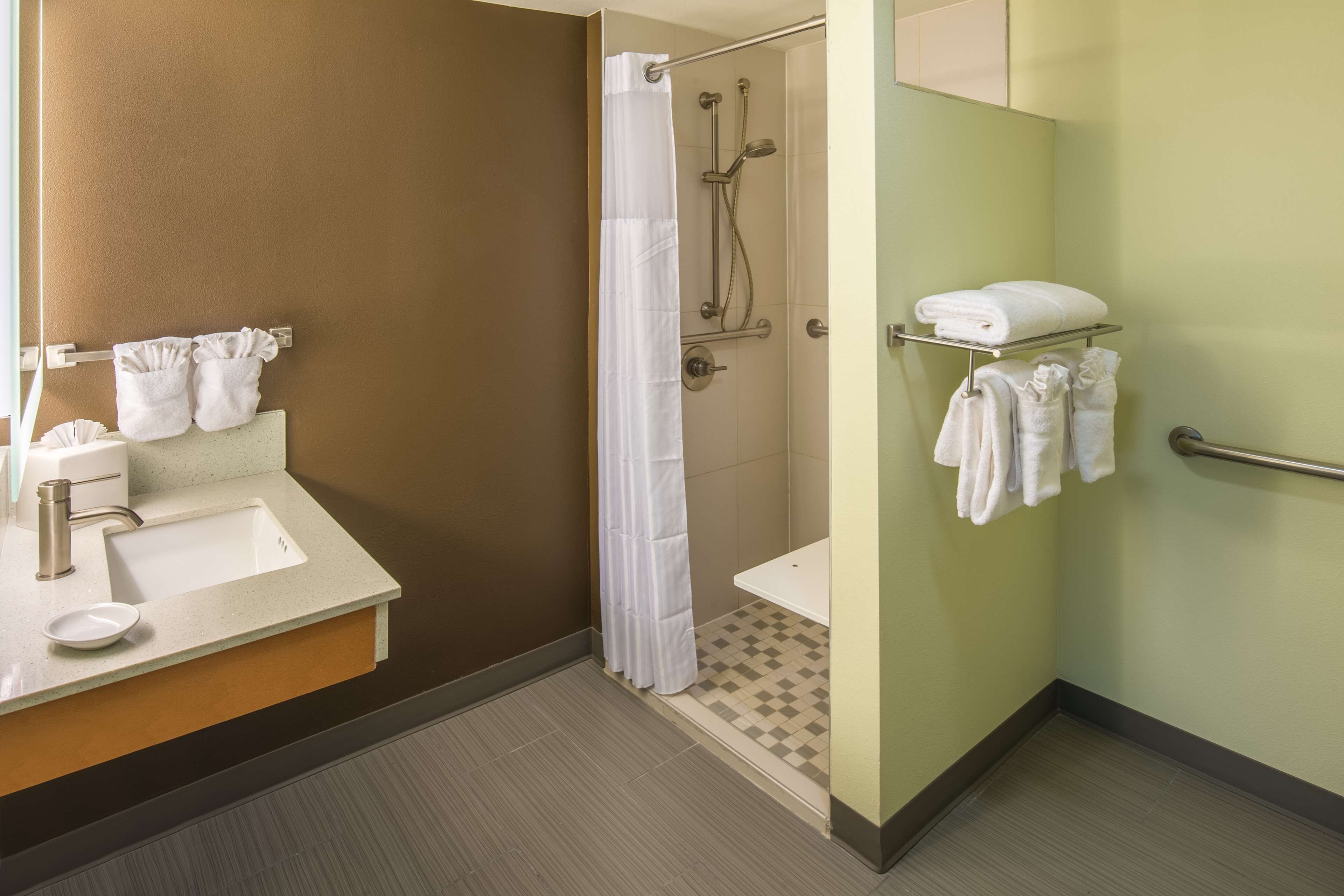 A bathroom with a sink, mirror, towel rack, shower, and toilet.