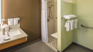 A bathroom with a sink, mirror, towel rack, shower, and toilet.
