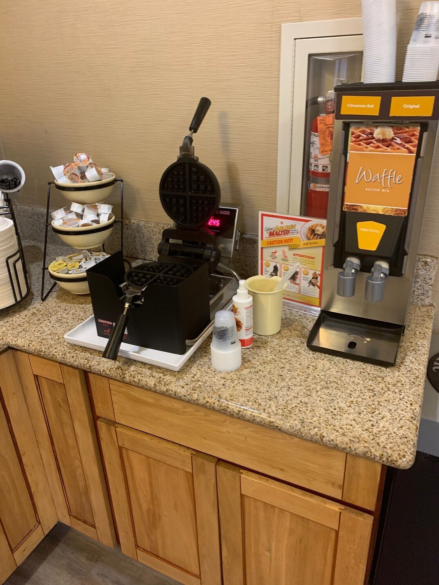 A waffle station with a digital clock, a self-service beverage dispenser, and a menu board.